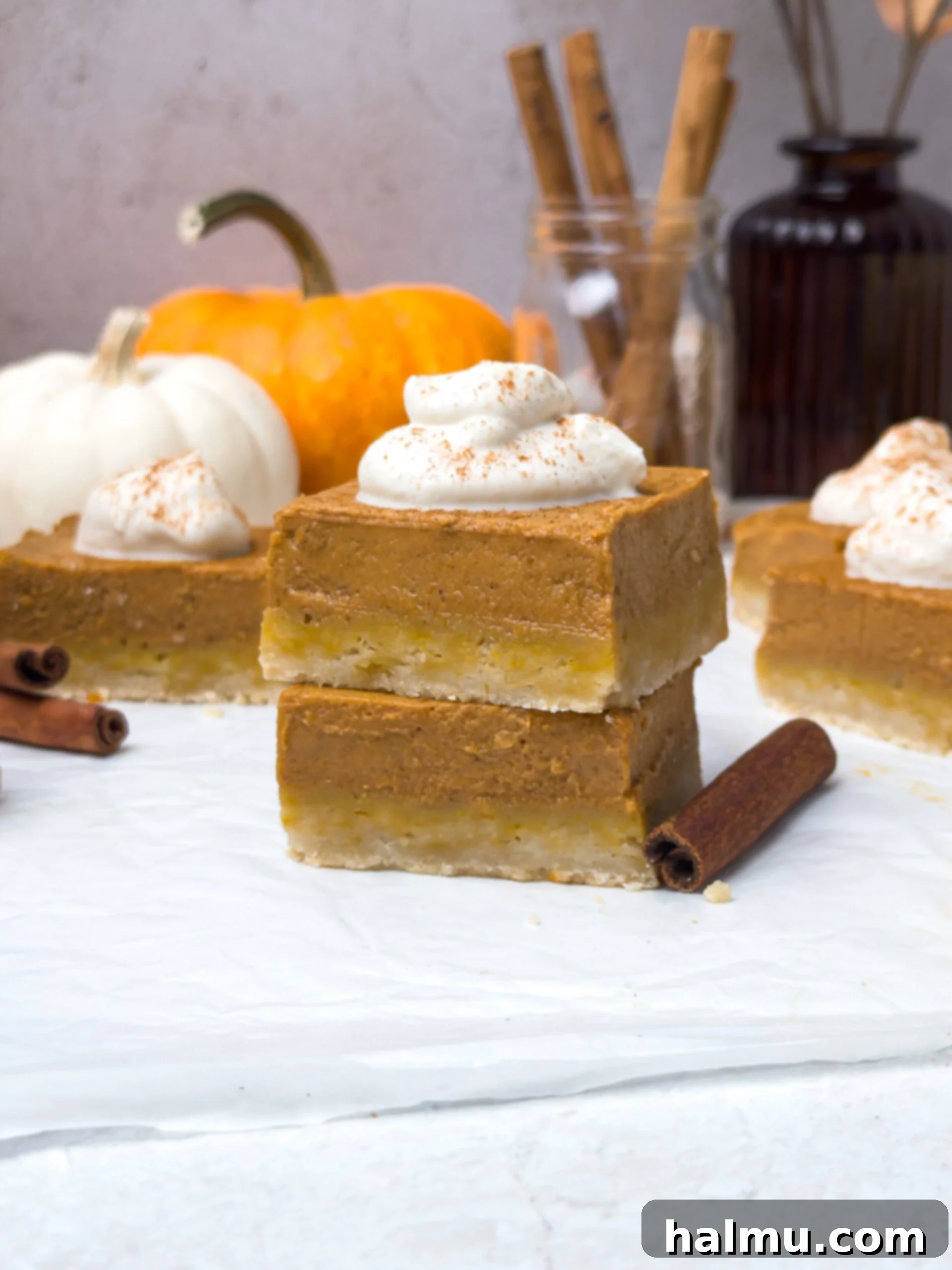 A full baking pan of pumpkin pie bars cooling, with several slices already cut, ready for serving.